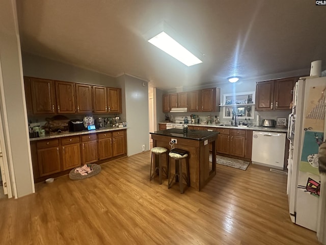 kitchen featuring sink, white appliances, a breakfast bar area, a center island, and light hardwood / wood-style floors