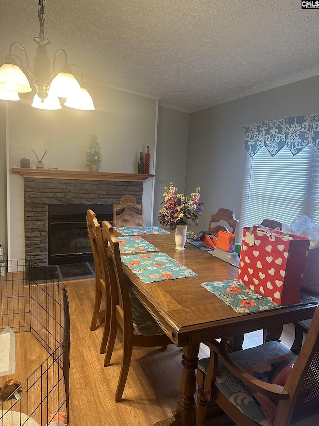 dining room with hardwood / wood-style floors, a stone fireplace, ornamental molding, and a textured ceiling