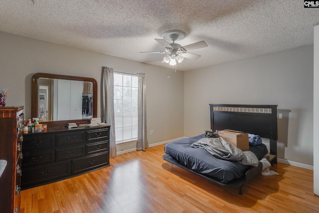 bedroom with ceiling fan, a textured ceiling, and light hardwood / wood-style flooring