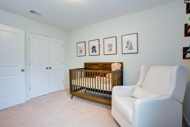 carpeted bedroom featuring a nursery area and a closet