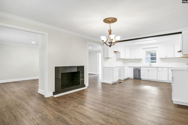 kitchen with white cabinetry, hanging light fixtures, a tiled fireplace, crown molding, and dark wood-type flooring