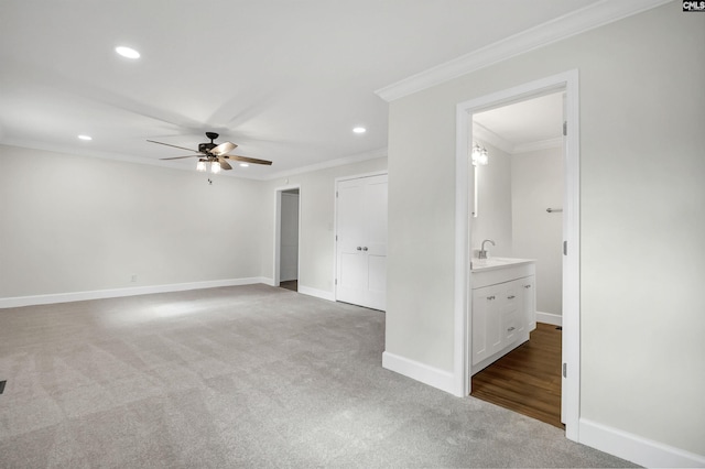 carpeted empty room featuring crown molding, ceiling fan, and sink