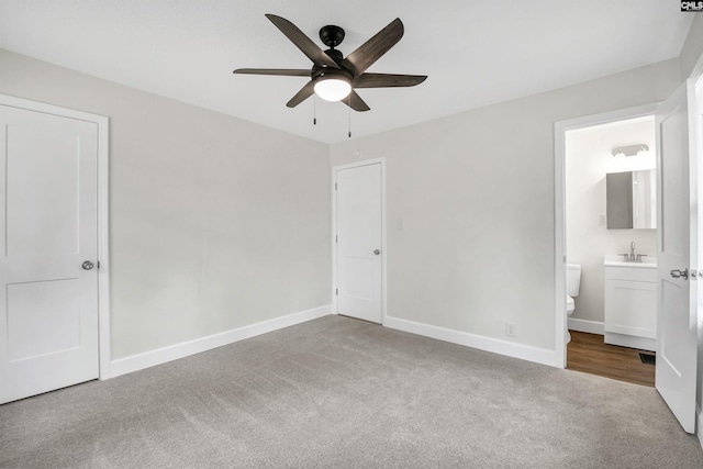 unfurnished bedroom with connected bathroom, sink, carpet floors, and ceiling fan