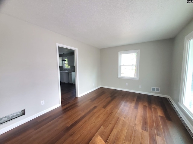 spare room featuring dark wood-type flooring and a textured ceiling