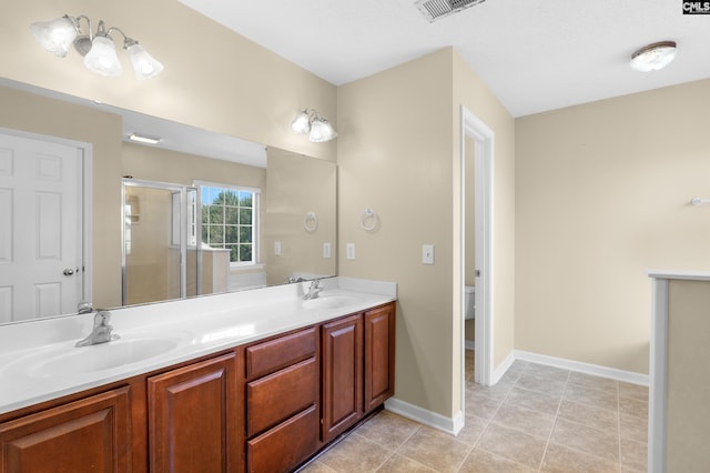 bathroom with tile patterned flooring, vanity, a shower with shower door, and toilet