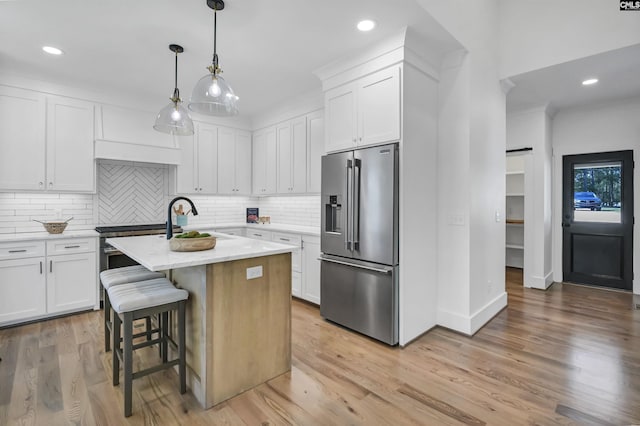 387 Bedford Way, Prosperity, SC 29127 - kitchen featuring a breakfast bar area, a kitchen island with sink, hanging light fixtures, white cabinets, and high end refrigerator