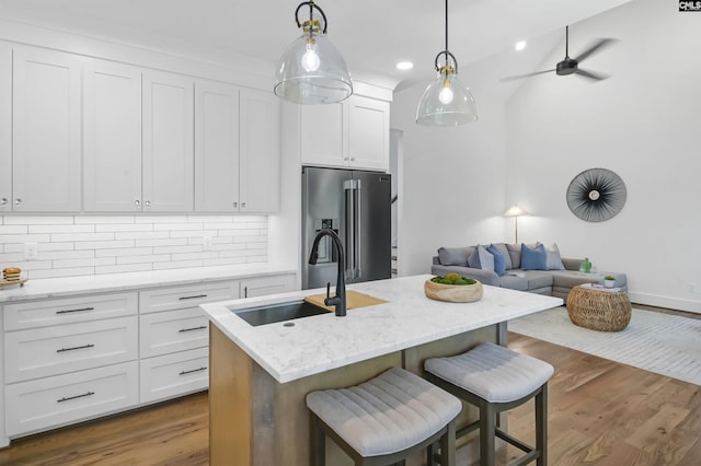387 Bedford Way, Prosperity, SC 29127 - kitchen with high quality fridge, sink, white cabinets, a kitchen island with sink, and light stone countertops