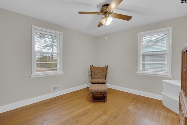 sitting room featuring ceiling fan, wood-type flooring, and a wealth of natural light