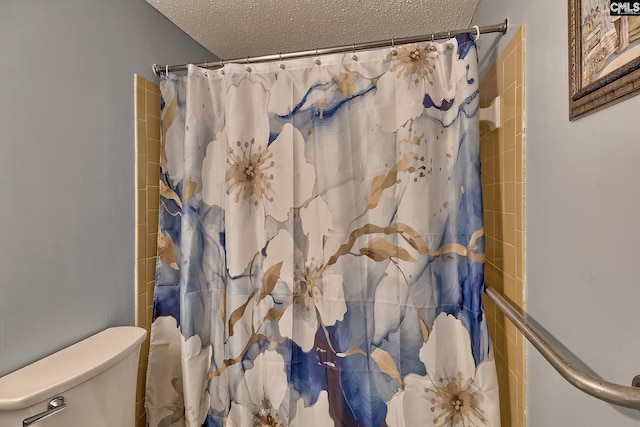 bathroom with toilet, a shower with shower curtain, and a textured ceiling