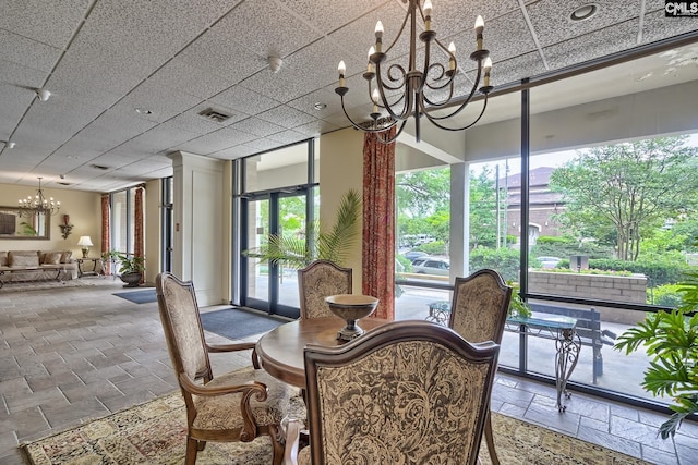 dining area with plenty of natural light, a chandelier, and a drop ceiling