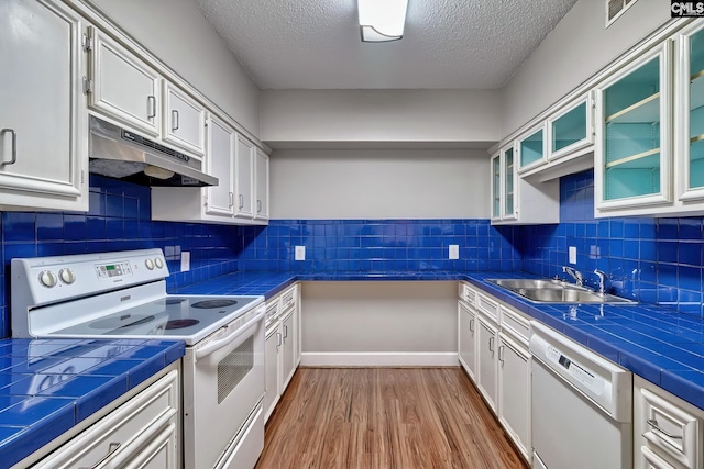 kitchen with white cabinetry, white appliances, tile countertops, and sink