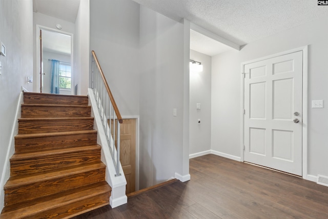 stairway with hardwood / wood-style flooring and a textured ceiling