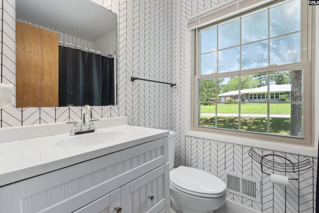 bathroom featuring a shower with curtain, vanity, toilet, and tile walls