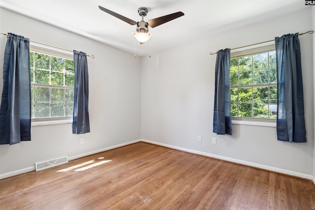 unfurnished room with hardwood / wood-style floors, a wealth of natural light, and ceiling fan