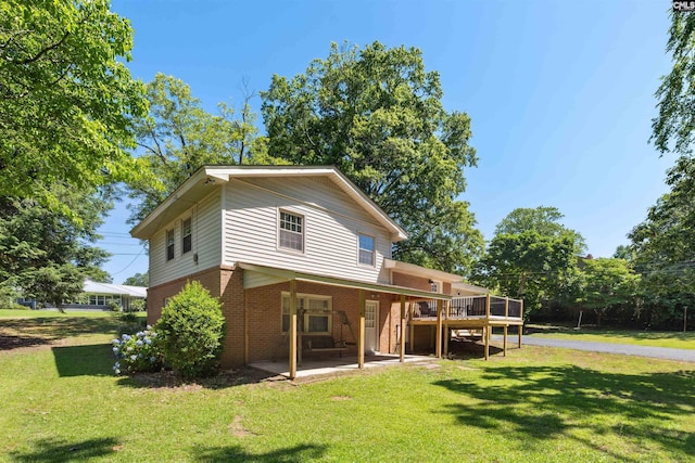 back of house featuring a wooden deck, a lawn, and a patio area