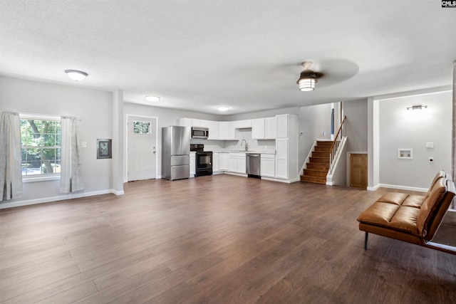 unfurnished living room with dark hardwood / wood-style floors, sink, and a textured ceiling