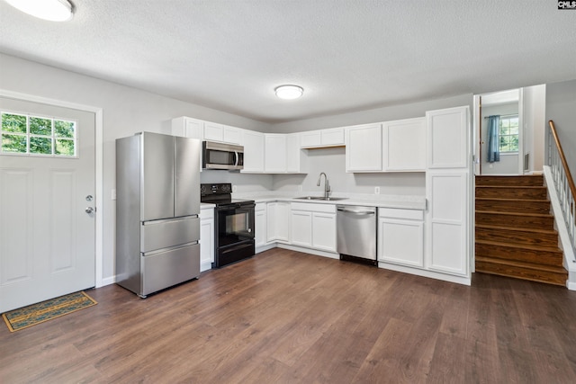 kitchen featuring appliances with stainless steel finishes, sink, white cabinets, dark wood-type flooring, and a textured ceiling