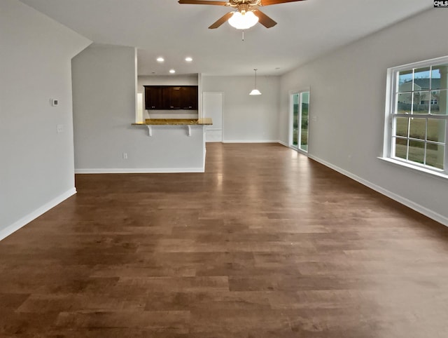 unfurnished living room featuring dark wood-type flooring and ceiling fan