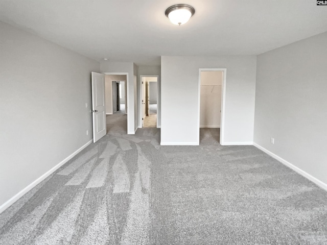 unfurnished bedroom featuring a closet, a spacious closet, and carpet flooring