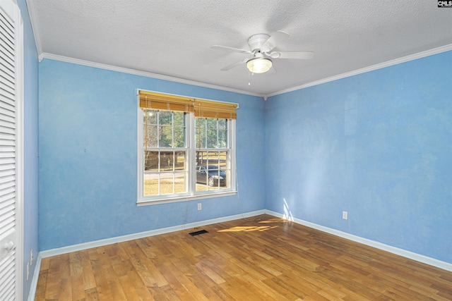 empty room with crown molding, ceiling fan, hardwood / wood-style floors, and a textured ceiling