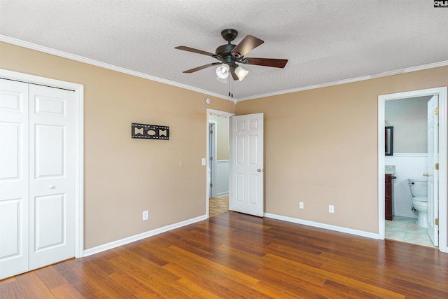 unfurnished bedroom featuring crown molding, a textured ceiling, dark hardwood / wood-style flooring, and a closet