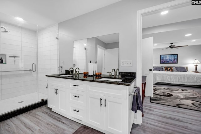 bathroom featuring vanity, hardwood / wood-style floors, a shower with door, and ceiling fan