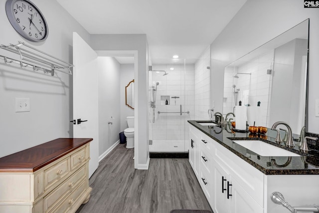 bathroom with an enclosed shower, vanity, wood-type flooring, and toilet