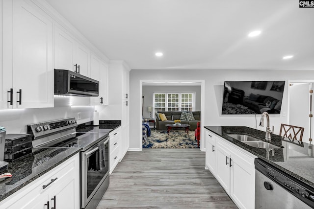 kitchen featuring white cabinetry, appliances with stainless steel finishes, sink, and dark stone countertops