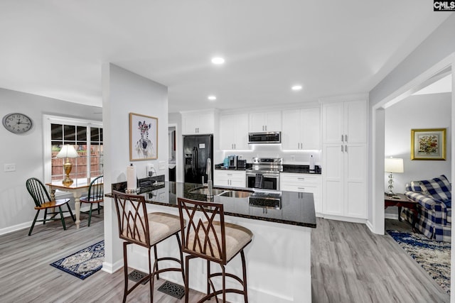 kitchen featuring stainless steel appliances, sink, white cabinets, and dark stone counters