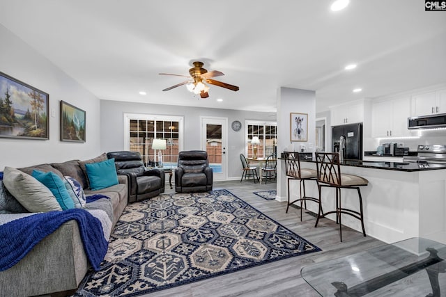 living room with sink, light hardwood / wood-style flooring, and ceiling fan