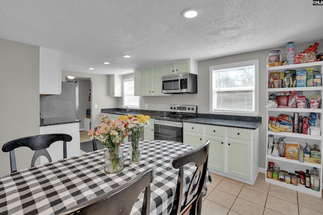 kitchen with sink, white cabinetry, stainless steel appliances, a textured ceiling, and light tile patterned flooring