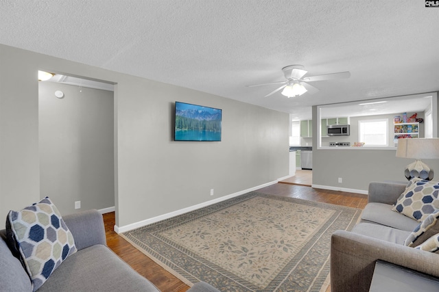 living room featuring wood-type flooring, a textured ceiling, and ceiling fan