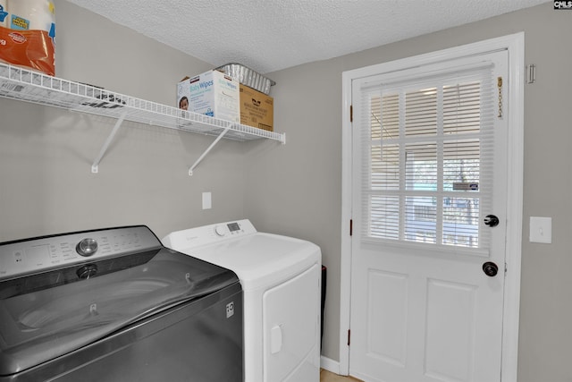 laundry room featuring a textured ceiling and washing machine and clothes dryer