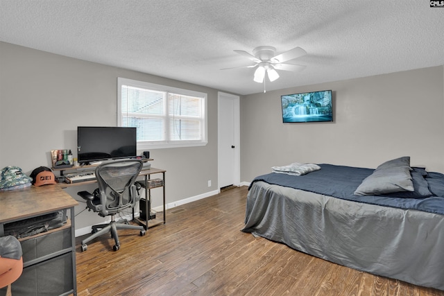 bedroom with ceiling fan, wood-type flooring, and a textured ceiling