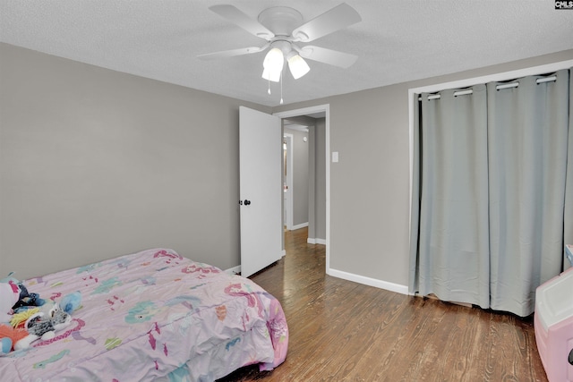 bedroom with ceiling fan, dark hardwood / wood-style floors, and a textured ceiling