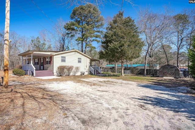 view of side of property with covered porch and a shed