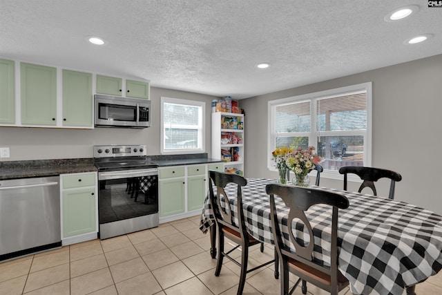 kitchen with stainless steel appliances, light tile patterned floors, a textured ceiling, and green cabinetry