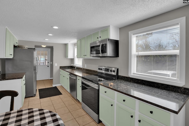 kitchen featuring light tile patterned flooring, sink, a textured ceiling, green cabinets, and stainless steel appliances