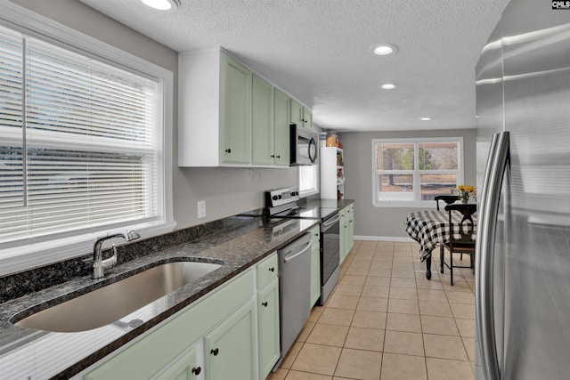 kitchen featuring light tile patterned flooring, stainless steel appliances, sink, and green cabinets