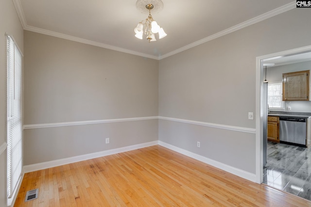 spare room featuring crown molding, a notable chandelier, and light hardwood / wood-style floors