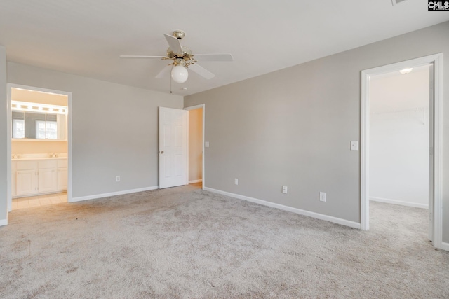 unfurnished bedroom with ceiling fan, connected bathroom, a walk in closet, light colored carpet, and a closet