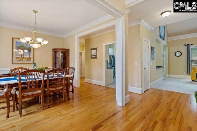 dining area with ornamental molding, a chandelier, and light hardwood / wood-style flooring