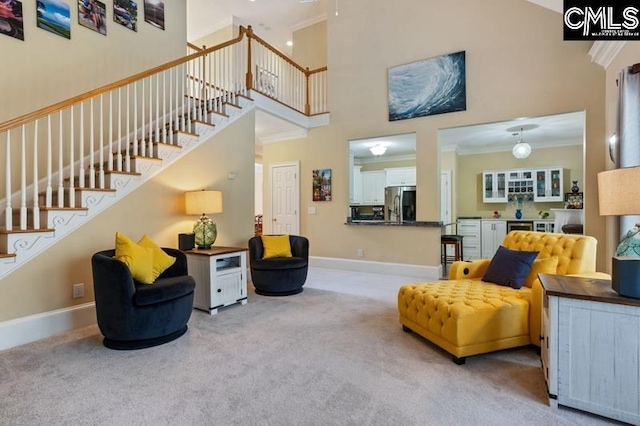 sitting room featuring ornamental molding, a towering ceiling, and light colored carpet