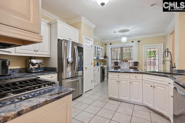 kitchen with sink, appliances with stainless steel finishes, white cabinetry, dark stone countertops, and ornamental molding