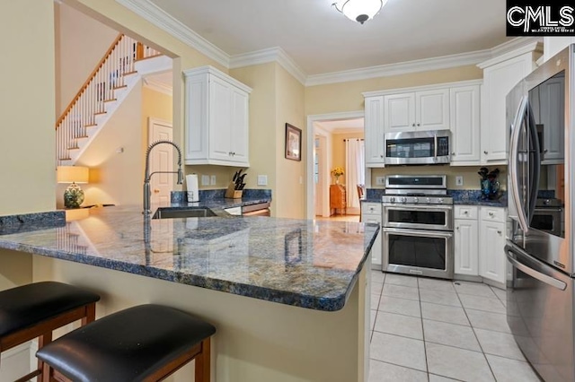 kitchen featuring sink, dark stone countertops, stainless steel appliances, white cabinets, and kitchen peninsula