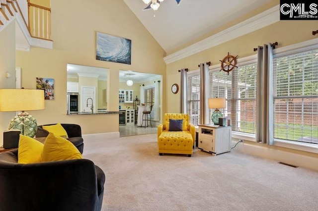 living area featuring crown molding, light carpet, ceiling fan, and high vaulted ceiling