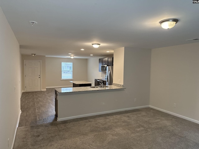 kitchen featuring dark carpet, sink, stainless steel appliances, and kitchen peninsula