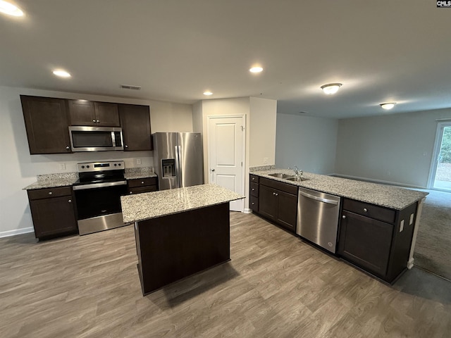 kitchen with kitchen peninsula, dark brown cabinetry, a kitchen island, sink, and appliances with stainless steel finishes