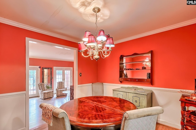 dining room with hardwood / wood-style flooring, ornamental molding, and a chandelier