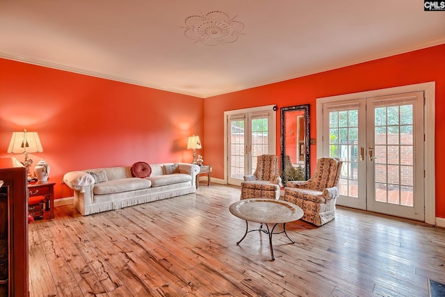 living room with french doors, ornamental molding, and light hardwood / wood-style floors